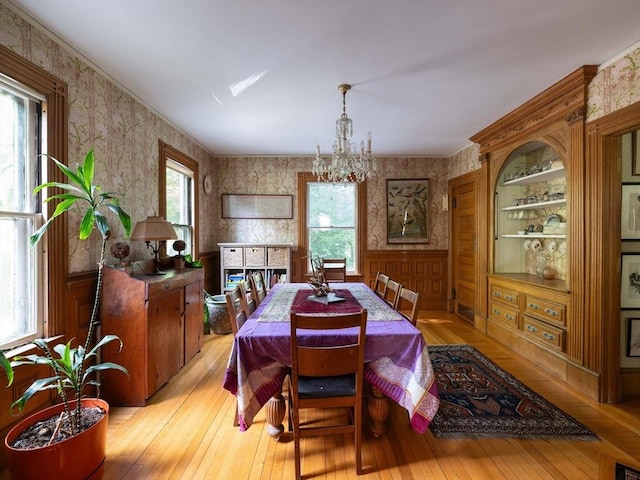 dining space with wallpapered walls, light wood-style floors, and a chandelier