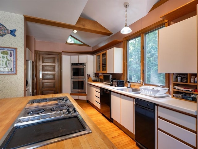 kitchen with appliances with stainless steel finishes, vaulted ceiling, white cabinets, light wood-type flooring, and hanging light fixtures