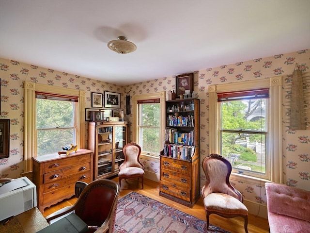 office area with wallpapered walls, healthy amount of natural light, wood finished floors, and baseboards