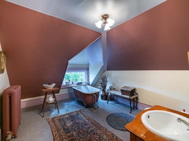 bathroom with radiator, a sink, a chandelier, a freestanding tub, and baseboards