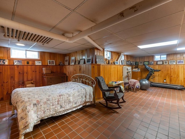 bedroom with wood walls, tile patterned flooring, and a paneled ceiling