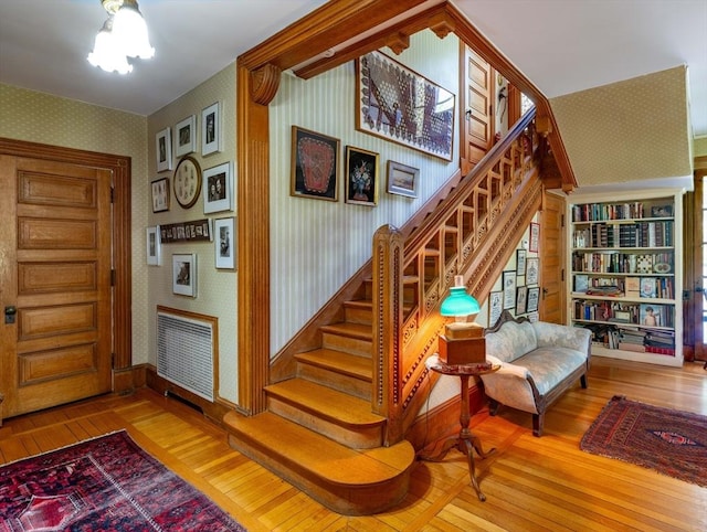 entrance foyer featuring wallpapered walls, wood-type flooring, stairway, and baseboards
