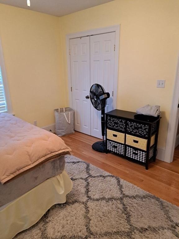 bedroom with baseboards, wood finished floors, and a closet