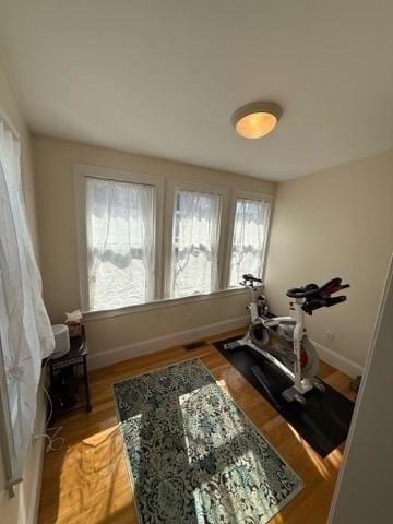 exercise room with baseboards and wood finished floors