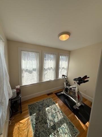 workout area with baseboards and light wood-style floors