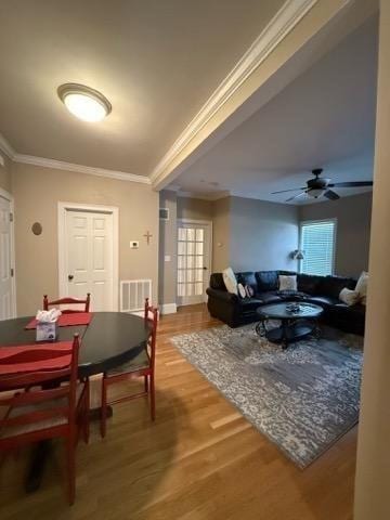 dining room featuring a ceiling fan, baseboards, wood finished floors, visible vents, and ornamental molding