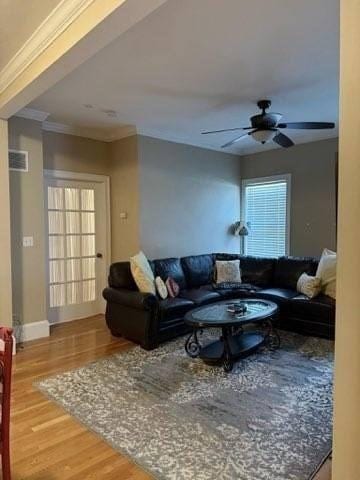 living room with crown molding, a ceiling fan, and wood finished floors
