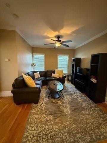 living room with baseboards, ornamental molding, ceiling fan, and light wood-style floors