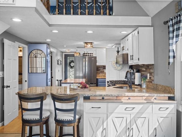 34 Lake Shore Dr S, Westford, MA 01886 - kitchen with freestanding refrigerator, a peninsula, white cabinetry, tasteful backsplash, and a sink