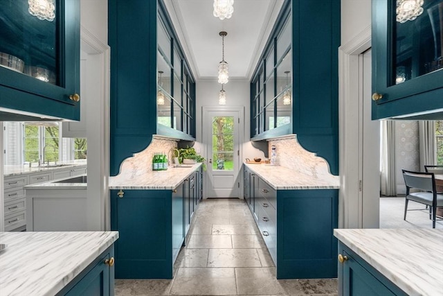 kitchen with backsplash, crown molding, blue cabinetry, and hanging light fixtures