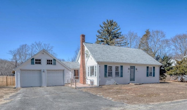 view of front of home with aphalt driveway, roof with shingles, a chimney, fence, and a garage