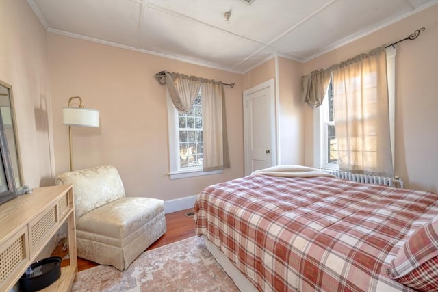 bedroom with crown molding, wood finished floors, and baseboards