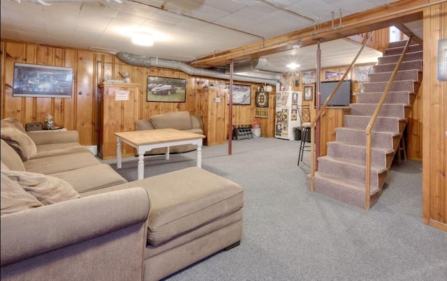 living area featuring stairway, carpet, and wooden walls