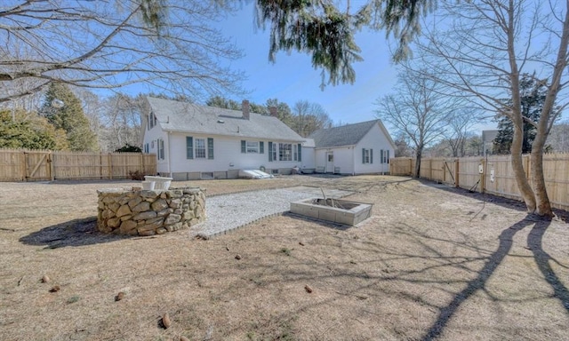 back of house with a fenced backyard and a chimney