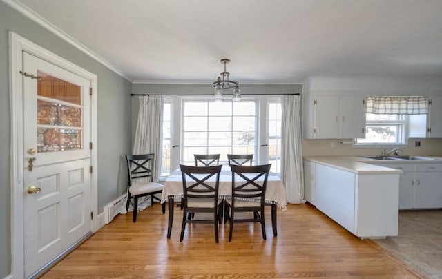 dining room featuring crown molding, light wood-style flooring, and an inviting chandelier