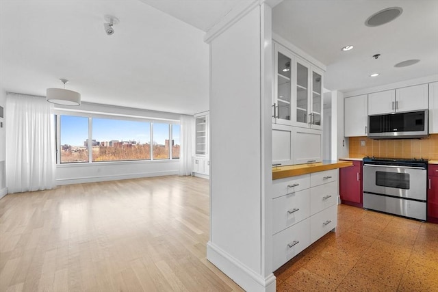 kitchen featuring appliances with stainless steel finishes, tasteful backsplash, white cabinetry, glass insert cabinets, and recessed lighting