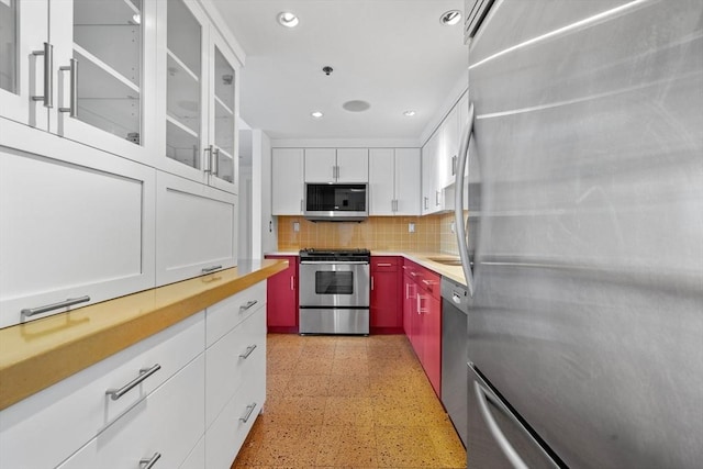 kitchen featuring appliances with stainless steel finishes, dark speckled floor, backsplash, recessed lighting, and white cabinetry