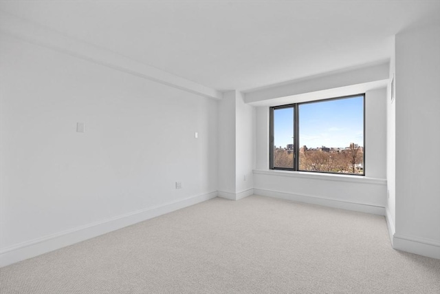 empty room featuring light colored carpet and baseboards