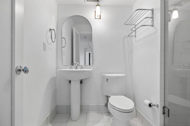 bathroom with toilet, baseboards, tile patterned flooring, and a shower