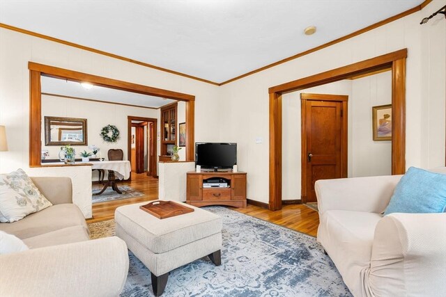 living room with light wood-type flooring, baseboards, and ornamental molding