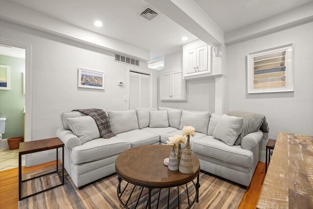 living room with recessed lighting, visible vents, and wood finished floors