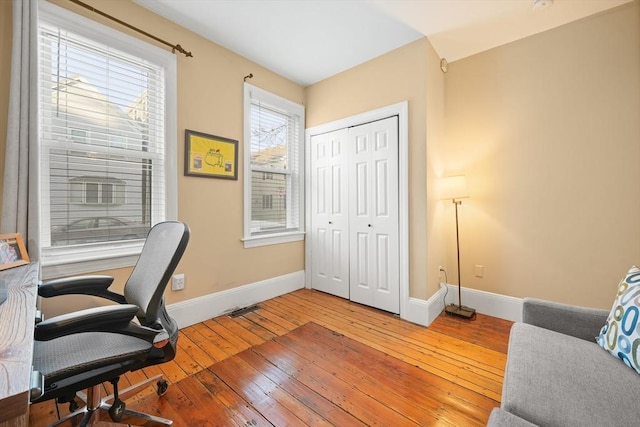 home office with baseboards, light wood-style flooring, and visible vents