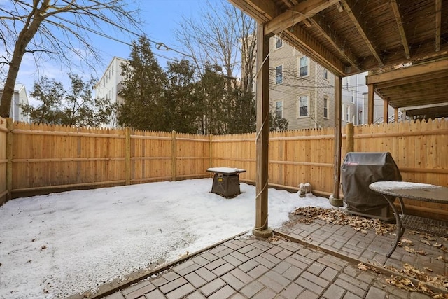 snow covered patio with a fenced backyard and grilling area