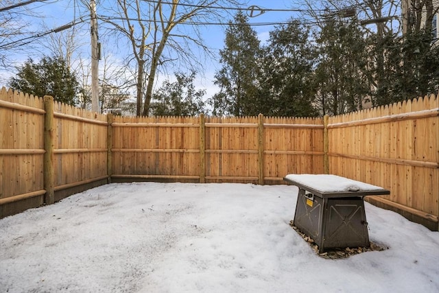 snow covered patio with a fenced backyard