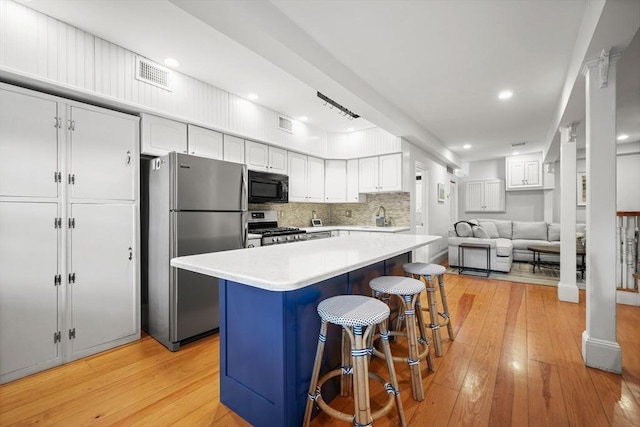 kitchen with visible vents, a kitchen breakfast bar, a sink, light wood-style flooring, and appliances with stainless steel finishes