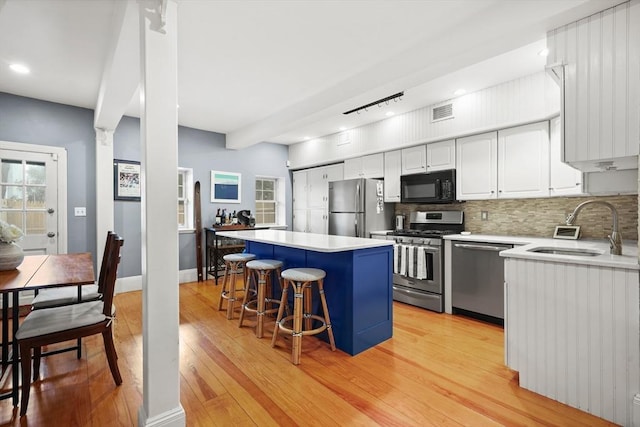 kitchen with a kitchen island, stainless steel appliances, a sink, and light wood-style flooring