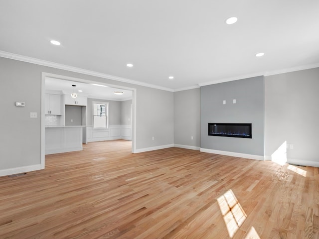 unfurnished living room featuring ornamental molding and light wood-type flooring