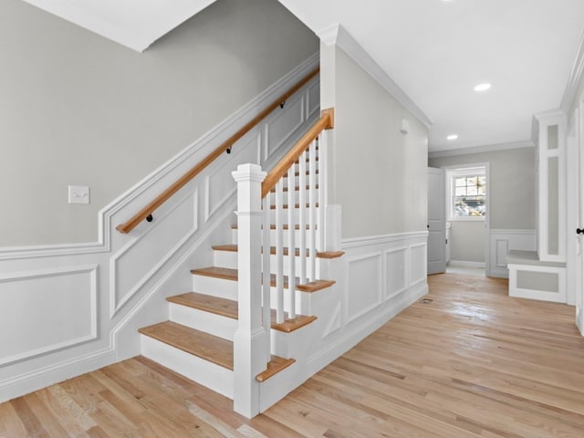 stairway with ornamental molding and hardwood / wood-style floors