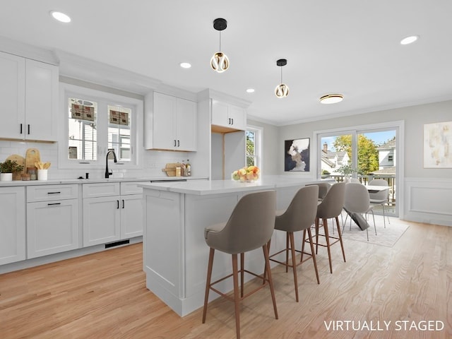 kitchen featuring white cabinetry, decorative light fixtures, and light wood-type flooring