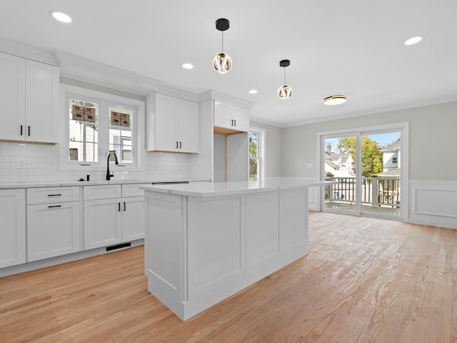 kitchen featuring decorative backsplash, white cabinets, light wood-type flooring, and pendant lighting