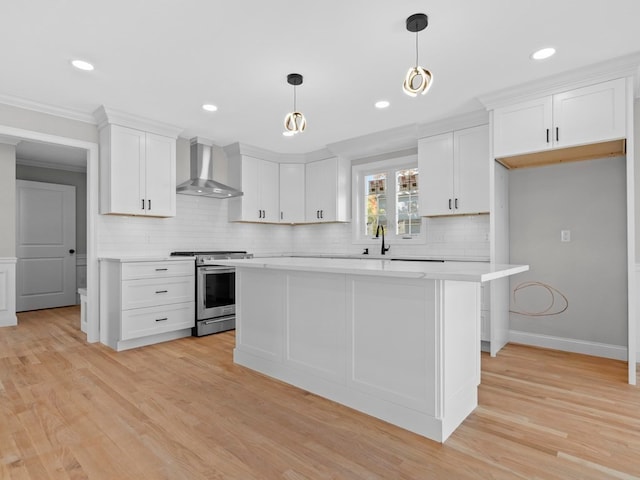 kitchen featuring white cabinetry, light hardwood / wood-style floors, wall chimney range hood, and stainless steel stove