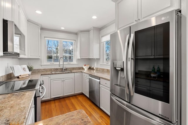 kitchen with sink, appliances with stainless steel finishes, white cabinets, and light wood-type flooring