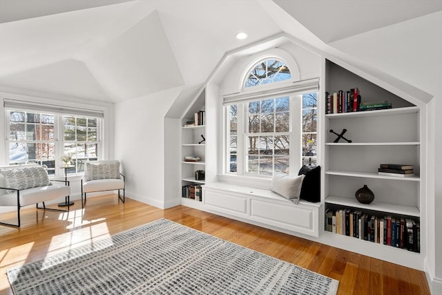 living area featuring lofted ceiling, built in features, and hardwood / wood-style floors