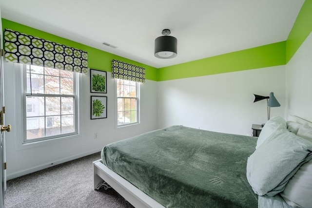 bedroom featuring carpet flooring, baseboards, visible vents, and multiple windows