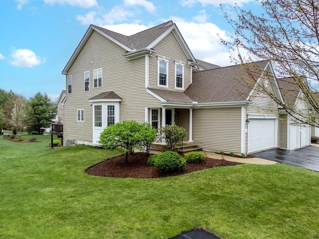 view of front of house with a shingled roof, an attached garage, driveway, and a front yard