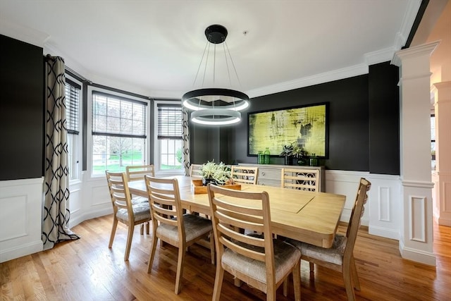 dining space with crown molding, a chandelier, decorative columns, and a decorative wall