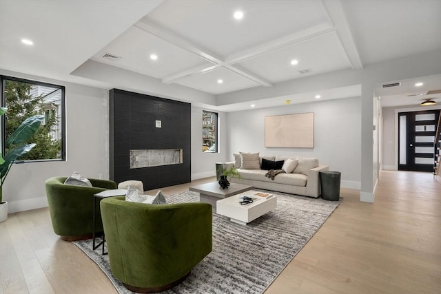 living room with a fireplace, beam ceiling, light wood-type flooring, and coffered ceiling