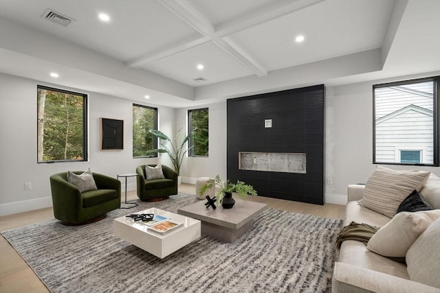 living room with beamed ceiling, a large fireplace, and light hardwood / wood-style floors