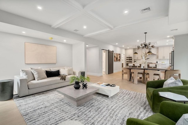 living room featuring coffered ceiling, a barn door, light wood-type flooring, beam ceiling, and a chandelier