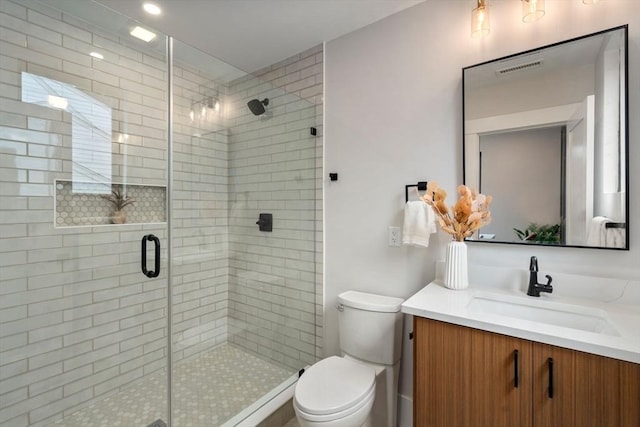 bathroom with vanity, toilet, and a shower with door