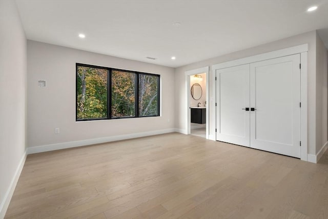 unfurnished bedroom featuring ensuite bath and light wood-type flooring