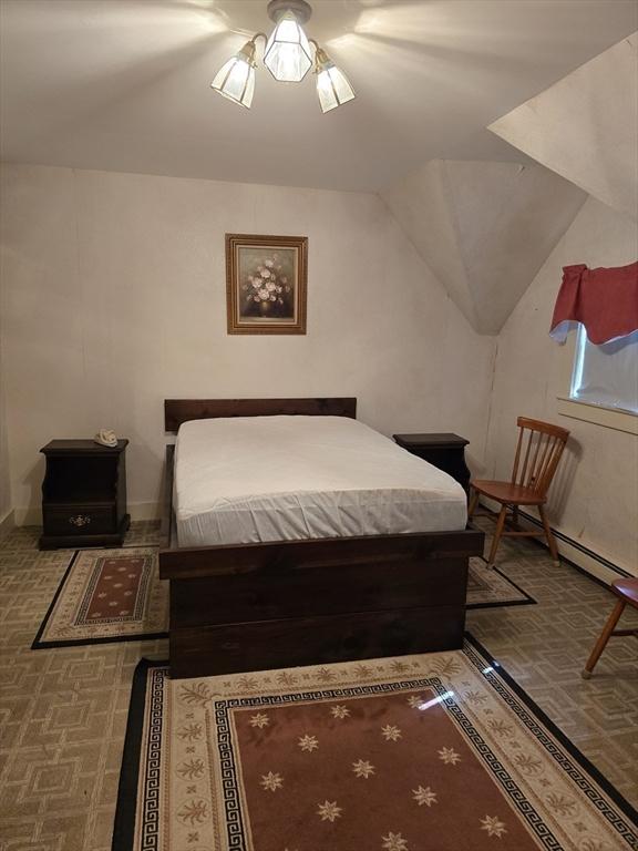 bedroom with lofted ceiling and a baseboard radiator