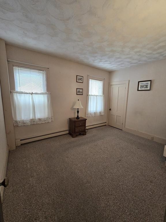 unfurnished room featuring carpet, baseboards, a baseboard radiator, a textured ceiling, and baseboard heating