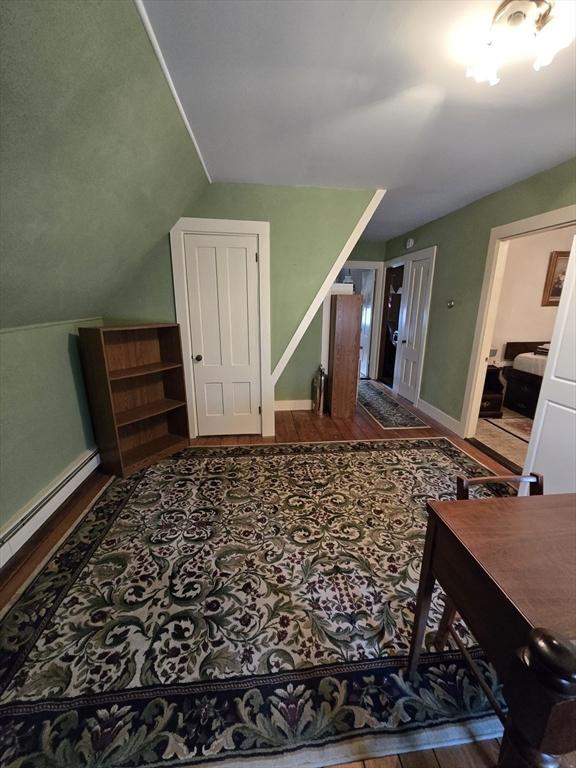 additional living space with baseboards, wood finished floors, and vaulted ceiling