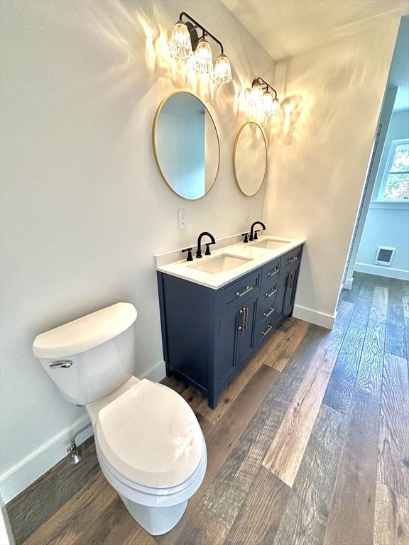 90 Bald Mountain Rd, Bernardston, MA 01337 - bathroom featuring wood finished floors, double vanity, toilet, baseboards, and a chandelier