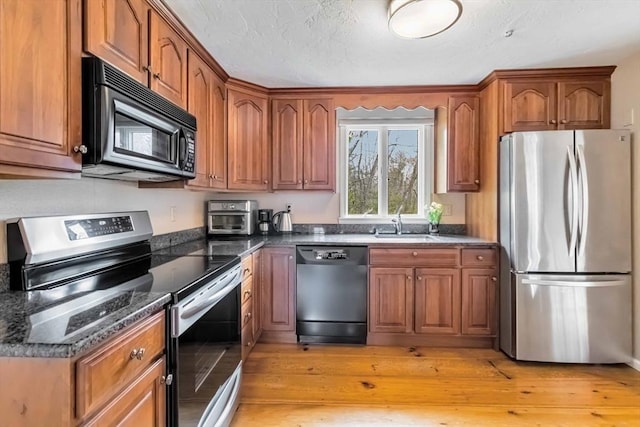 10 Mallard Rd, Acton, MA 01720 - kitchen featuring light wood finished floors, a sink, dark stone counters, stainless steel appliances, and brown cabinetry